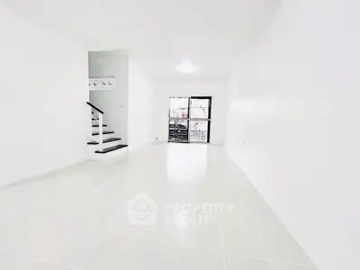 Spacious minimalist living room with white tiles and staircase, perfect for modern living.