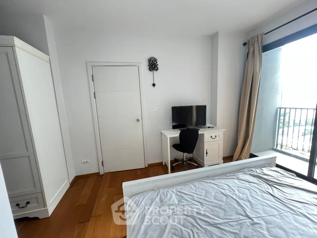 Spacious bedroom with balcony access and modern furnishings in a bright apartment.