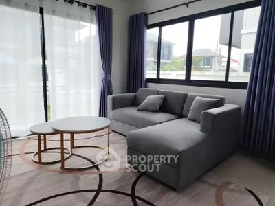 Modern living room with stylish gray sofa and elegant round coffee tables, featuring large windows and chic curtains.