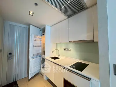 Modern kitchen with sleek white cabinets and built-in appliances in a compact layout.