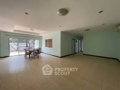Spacious open-plan living area with dining set and large windows for natural light.