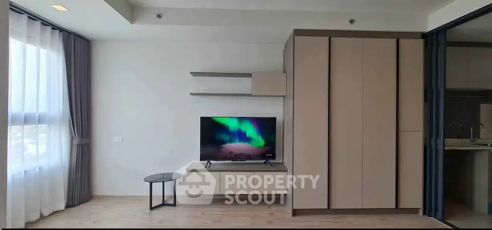 Modern living room with sleek TV unit and large window, offering a bright and airy ambiance.