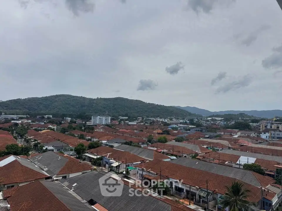 Scenic aerial view of suburban neighborhood with red-roofed houses and lush green hills.