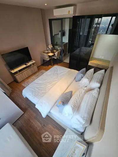 Modern bedroom with city view, featuring sleek furniture and cozy ambiance.