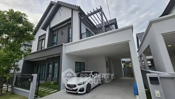 Modern two-story house with carport and sleek white car parked in driveway.