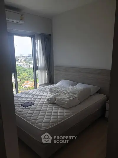 Cozy bedroom with large window offering stunning city views, featuring a comfortable bed and modern decor.