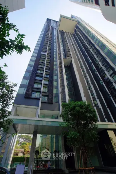 Stunning modern high-rise building with sleek architecture and lush greenery at the entrance.