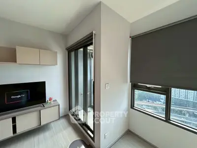 Modern living room with sleek TV setup and large window offering city view