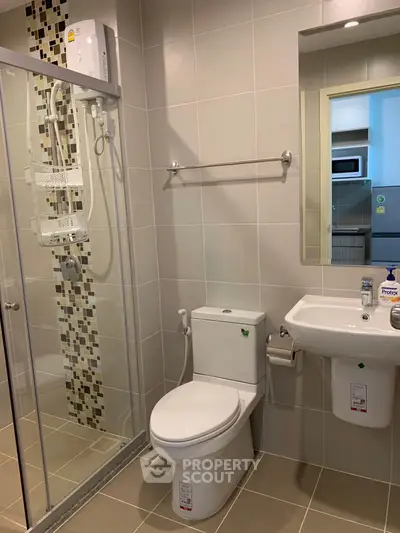 Modern bathroom with glass shower and sleek fixtures in contemporary apartment.