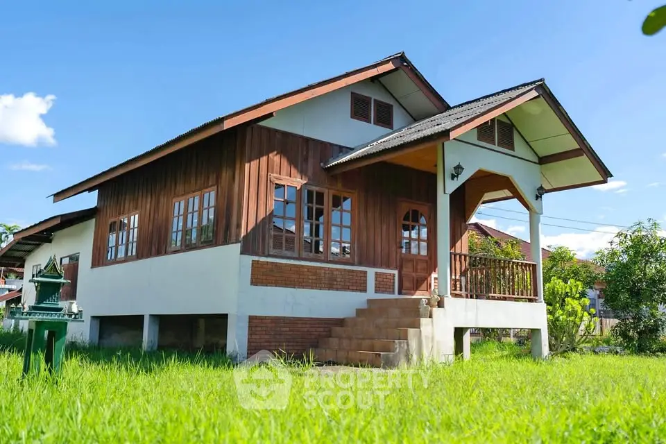 Charming wooden house with elevated porch and lush green lawn, perfect for serene living.