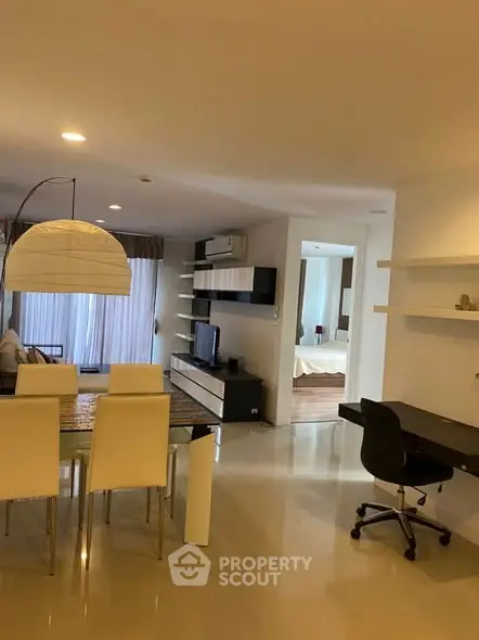 Modern open-plan living room with dining area and study desk, featuring sleek furniture and ambient lighting.