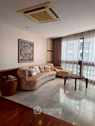 Spacious living room with elegant sofa and large window, perfect for relaxation.