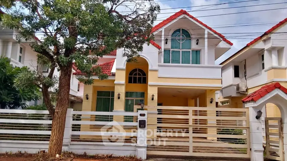 Charming two-story house with red roof and spacious front yard in a serene neighborhood.