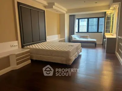 Spacious bedroom with elegant wood flooring and large window offering natural light.