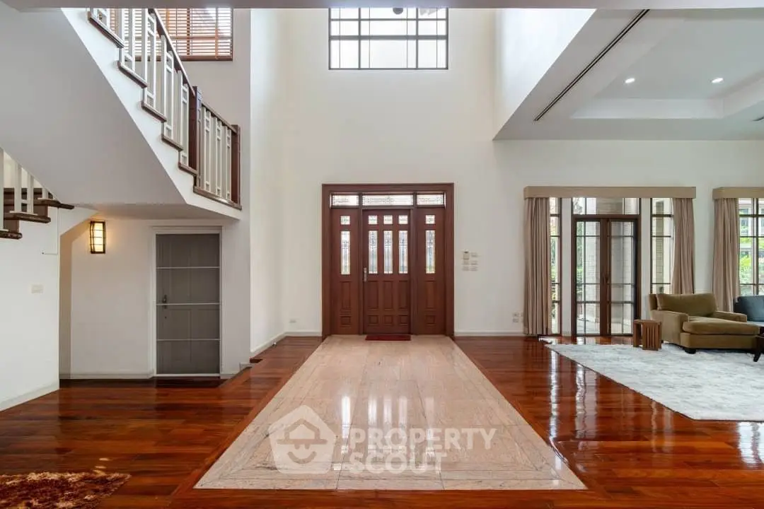 Elegant spacious living room with polished hardwood floors, high ceilings, and abundant natural light streaming through large windows, perfect for luxurious living.
