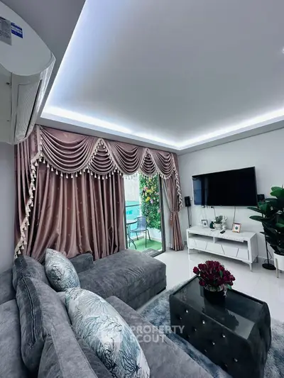 Luxurious living room with plush gray sofa, elegant drapes, and modern TV setup.