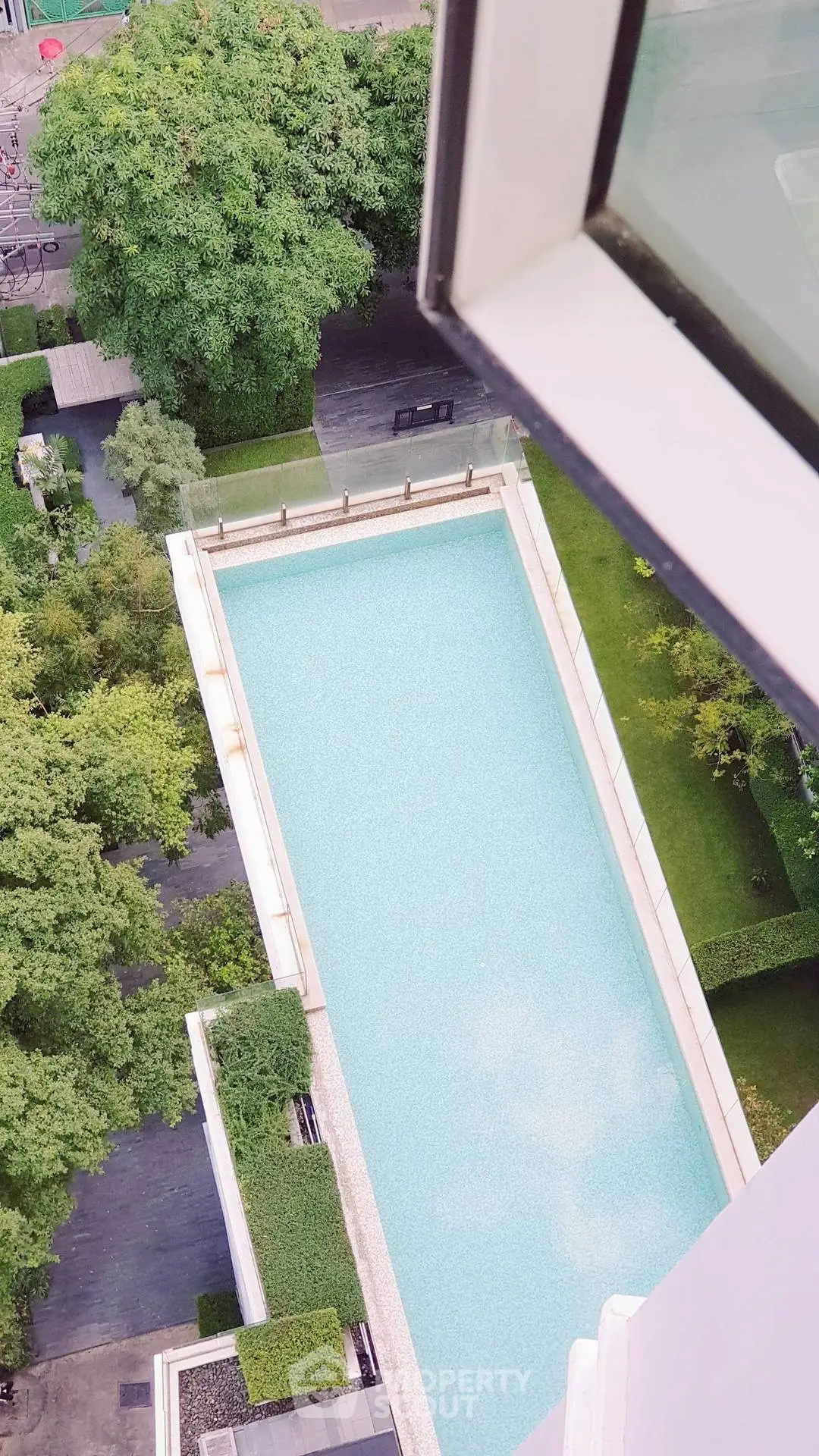 Stunning aerial view of a luxurious swimming pool surrounded by lush greenery, perfect for relaxation and leisure.