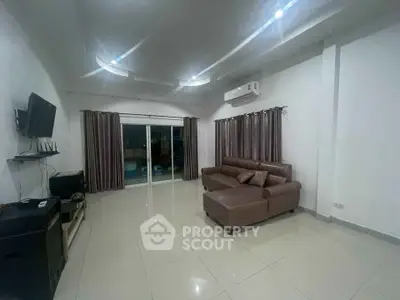 Spacious living room with modern sofa and wall-mounted TV, perfect for relaxation.