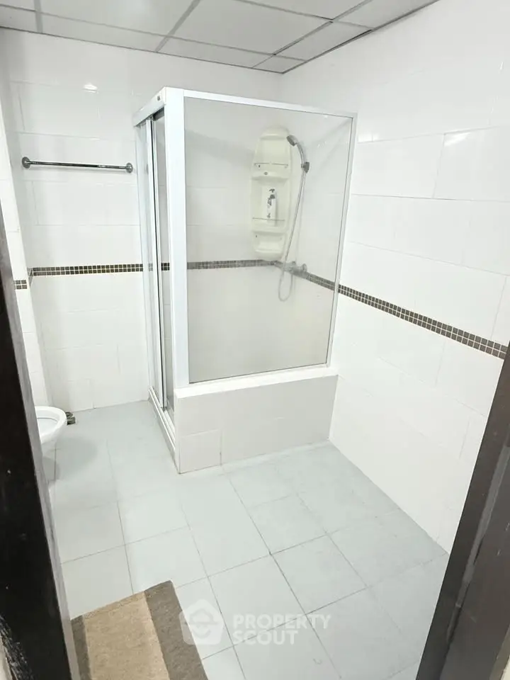 Spacious bathroom with modern shower enclosure and tiled walls.