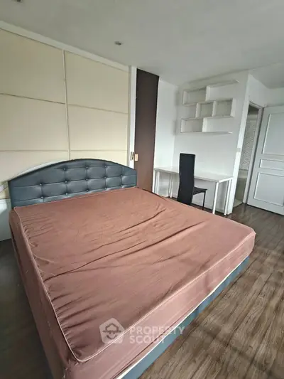 Spacious bedroom with modern decor and study area, featuring a large bed and sleek flooring.
