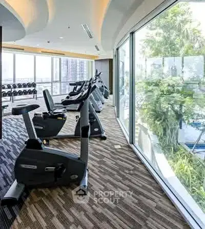 Spacious gym with modern equipment and large windows offering a scenic view.