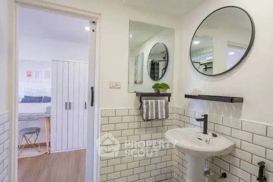 Modern bathroom with stylish sink and mirror, leading to a cozy study area.