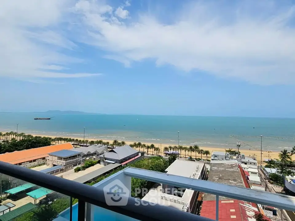 Stunning beachfront view from a high-rise balcony overlooking the ocean and palm-lined shore.