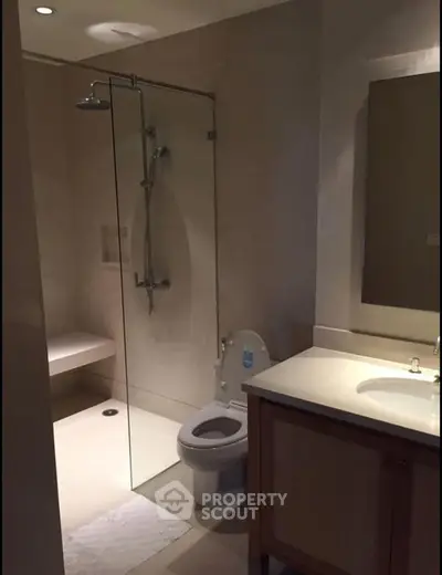 Modern bathroom with glass shower and sleek vanity in contemporary home.