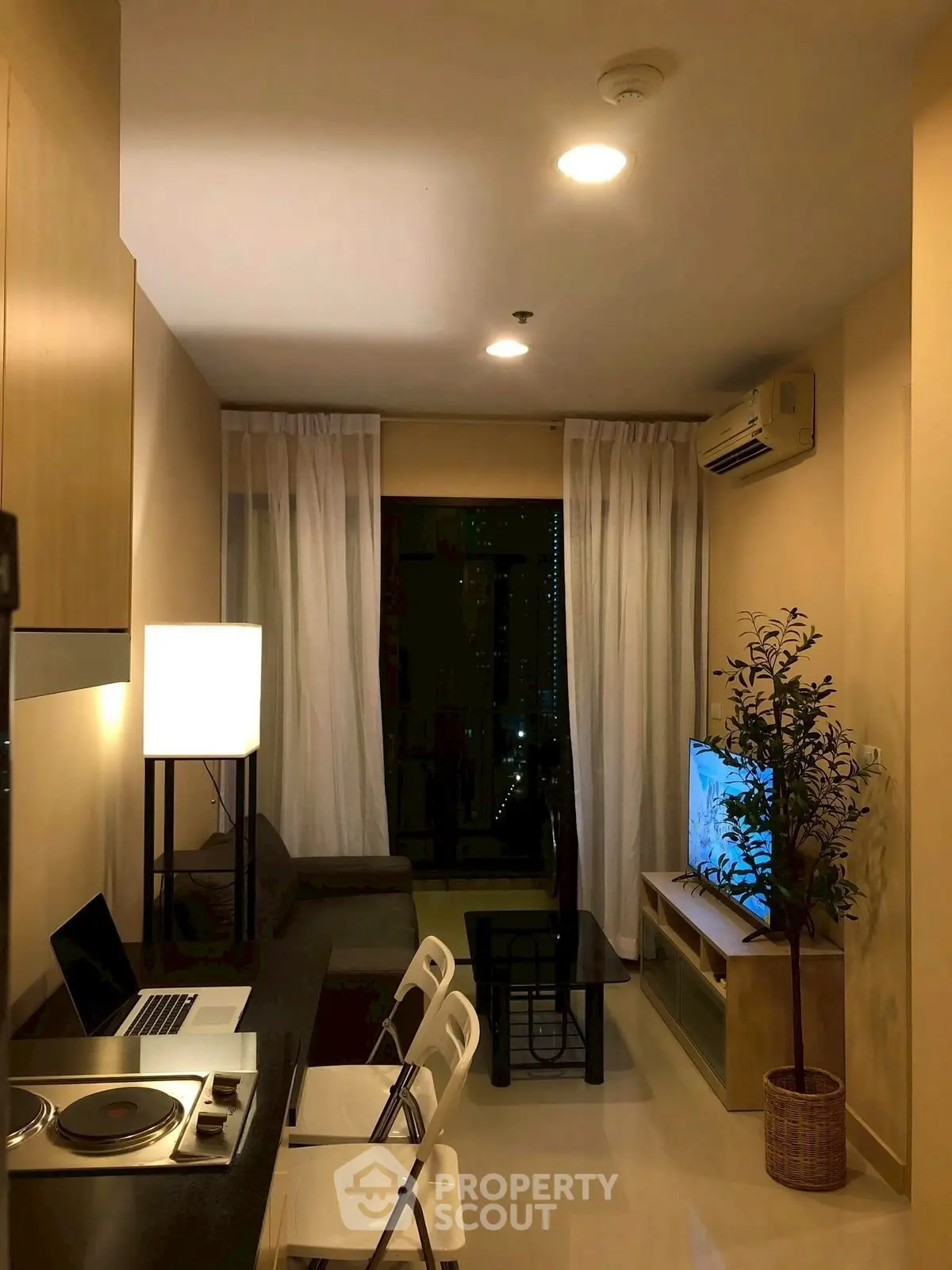 Cozy modern living room with open kitchen and city view, ideal for urban living.