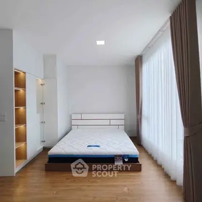 Spacious bedroom with large windows and modern design in a bright apartment.