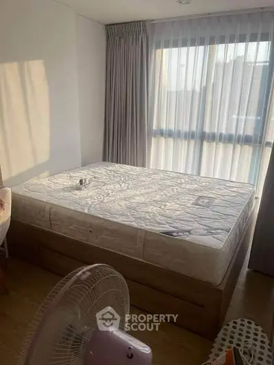 Cozy bedroom with large window and natural light, featuring a comfortable bed and modern decor.