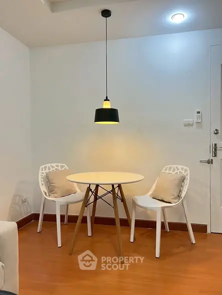 Cozy dining nook with modern chairs and pendant light in a stylish apartment.