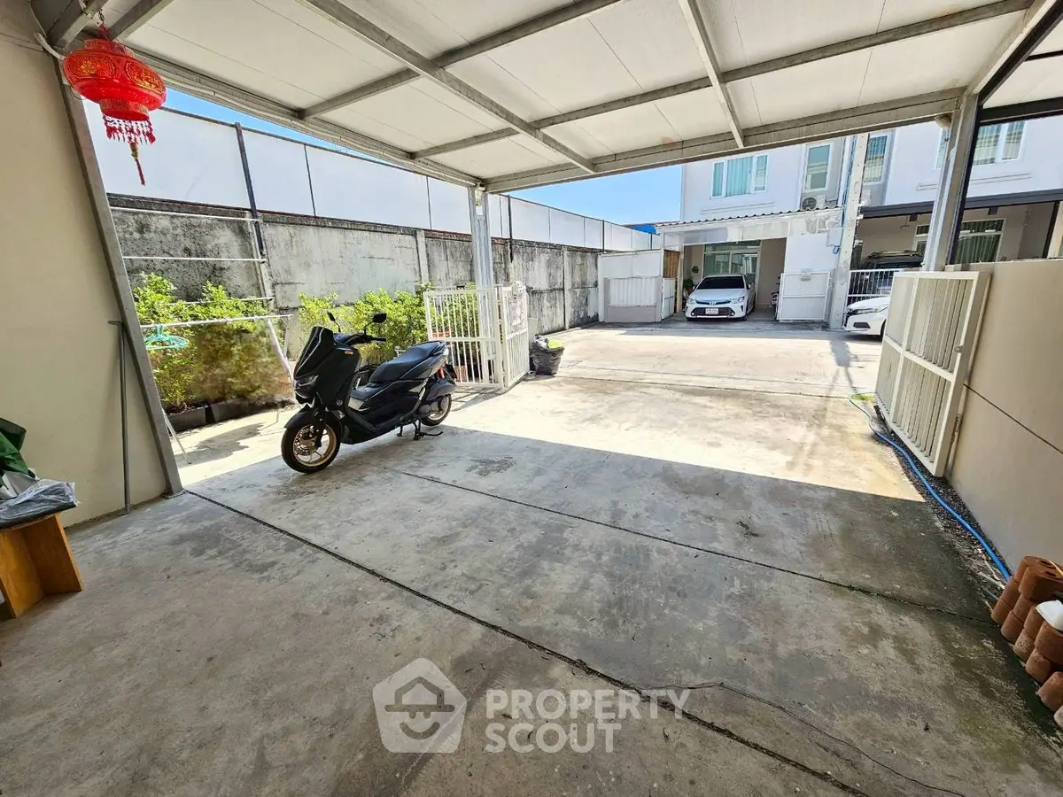 Spacious covered parking area with scooter and car access in modern residential property.