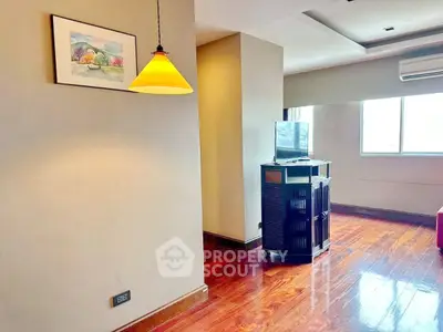 Spacious living room with wooden flooring and modern lighting in a stylish apartment.