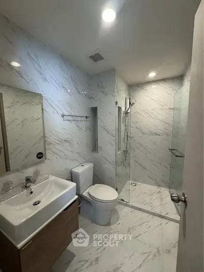 Modern bathroom with marble tiles and glass shower enclosure