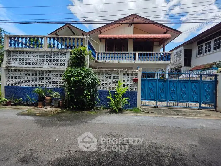 Charming two-story house with blue accents and lush greenery in a serene neighborhood.