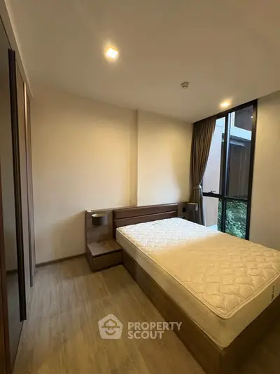 Cozy bedroom with large window and modern furnishings in a stylish apartment.