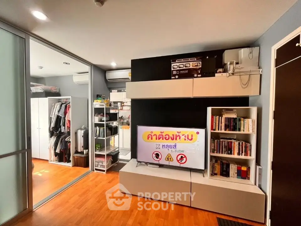 Modern living room with sleek storage, TV, and wooden flooring in a stylish apartment.