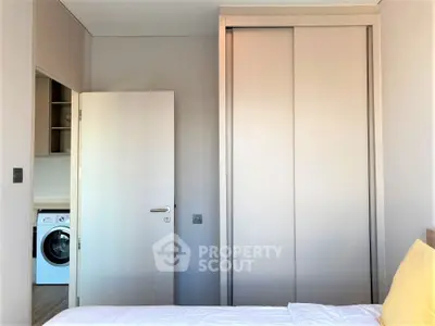 Modern bedroom with built-in wardrobe and washing machine view