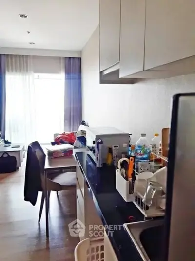 Modern kitchen with sleek countertops and dining area in a cozy apartment setting.