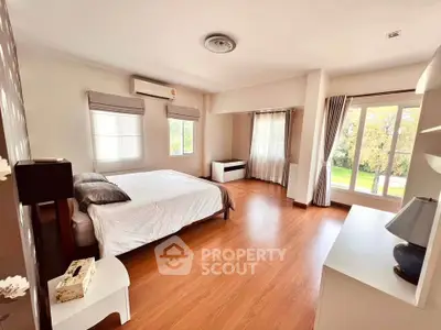Spacious bedroom with large windows and wooden flooring in a modern home.