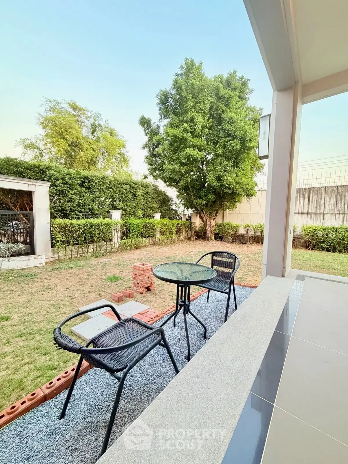 Charming garden view from a cozy patio with outdoor seating, perfect for relaxation and entertaining.