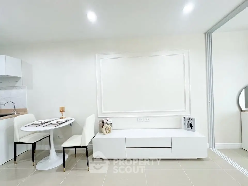 Modern minimalist living room with sleek white furniture and dining area