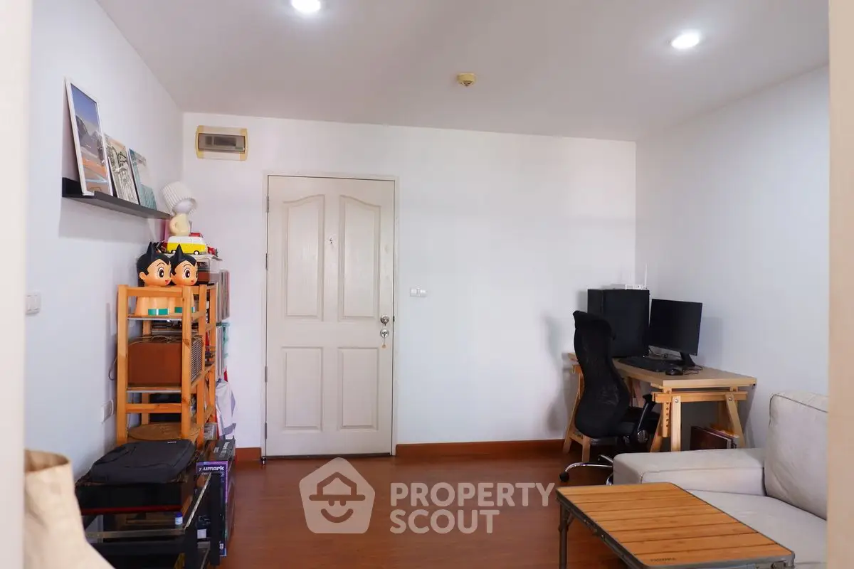 Cozy living room with wooden flooring and modern decor, featuring a comfortable sofa and a home office setup.