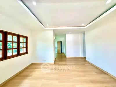 Spacious and bright living room with wooden flooring and large windows in modern home.