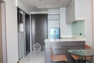 Modern compact kitchen with sleek design and glass dining table in a stylish apartment.