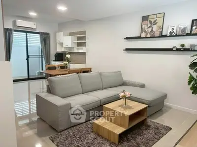 Modern living room with sleek grey sofa and stylish decor in open layout apartment.