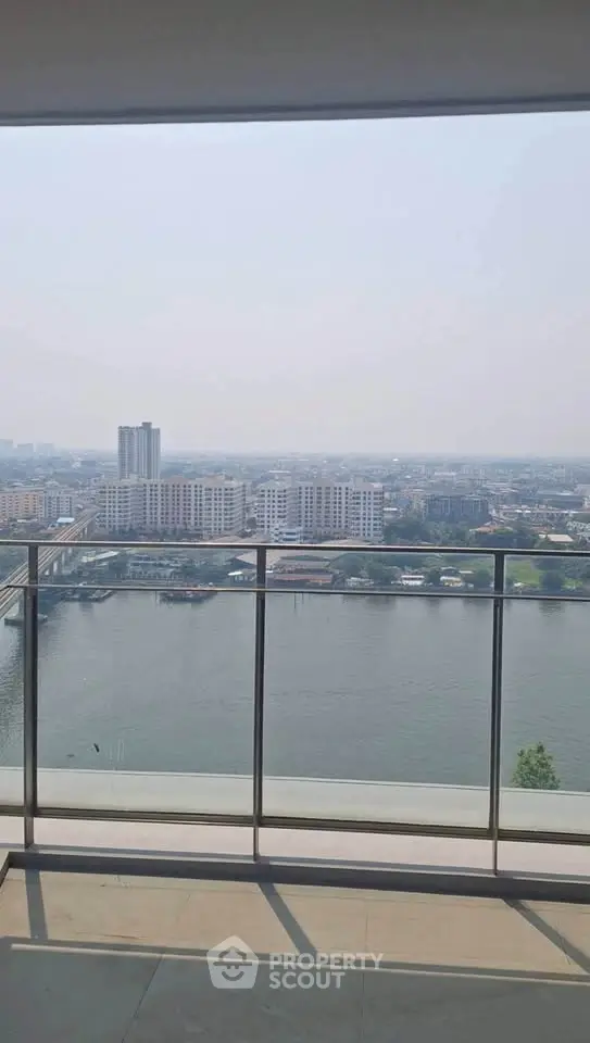 Stunning high-rise balcony view overlooking a serene river and cityscape, perfect for urban living.