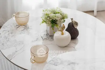 Elegant marble table with decorative vases and cups in a stylish interior setting.