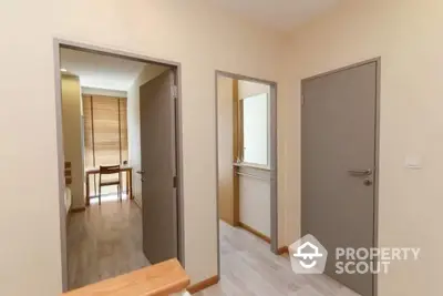 Spacious hallway leading to modern rooms with wooden flooring and neutral walls.